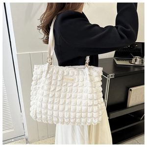 Detail of white bubble textured tote bag featuring a gold rectangle fashion label