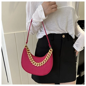 Macro detail of magenta crescent bag with thick gold chain and leather texture