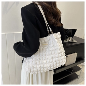 Close-up of white pleated bubble texture fabric and gold fashion label on the shoulder bag