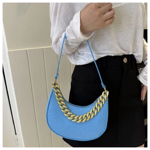 Close-up of bright blue leather crescent bag with decorative gold chain strap
