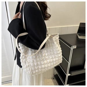 Detailed view of white quilted shoulder bag with bubble texture and slim straps for work