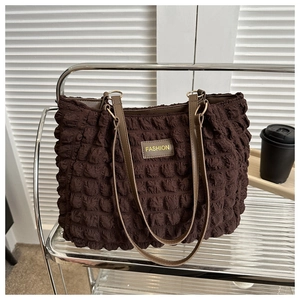 Detailed view of the dark brown bubble textured tote bag on a stainless steel shelf