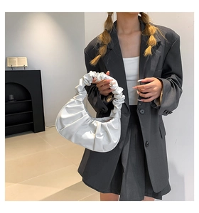 Detail of white scrunchie cloud bag showing pleated leather texture on a female model