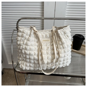 Detail of white bubble texture tote bag with FASHION leather label and gold hardware