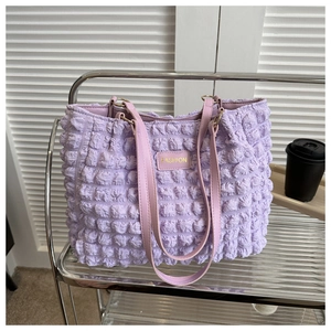 Detail of light purple pleated shoulder bag with bubble texture and gold fashion plaque