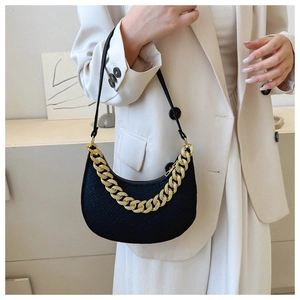 Detail of black crescent shoulder bag with bold gold chain and textured leather finish