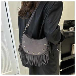 Détail du sac bandoulière en daim gris avec de longues franges et des œillets dorés