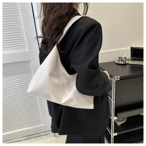 Minimalist white vegan leather shoulder bag styled on a model in a modern home interior