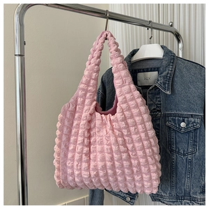 Détail de la texture gaufrée rose clair sur un sac cabas élégant pour femme
