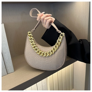 Macro shot of beige hobo bag with embossed texture and chunky gold chain strap