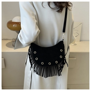 Détail du sac à franges noir avec anneaux métalliques dorés et texture en daim souple