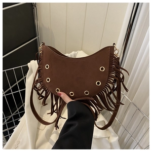 Détail d'un sac hobo en daim marron avec franges bohèmes et œillets dorés