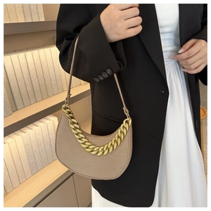 Detail of oatmeal half-moon bag with chunky gold chain strap and textured leather finish