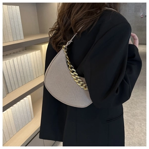 Detail of grey half-moon underarm bag with gold chain and snake skin leather texture