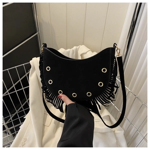 Detail view of black crescent tassel shoulder bag with golden metal rings and suede texture