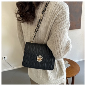 Schwarze Stepptasche mit V-Naht-Design und goldener Kette an einem Model präsentiert