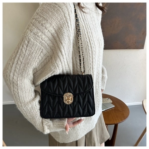 Detail der schwarzen Stepptasche mit goldenem Drehverschluss und Kettenriemen-Optik
