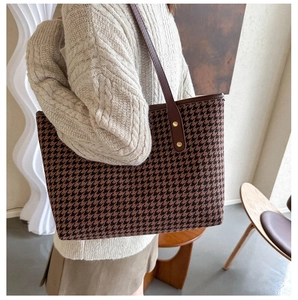 Detail of houndstooth tote bag with brown leather straps and gold rivets for women