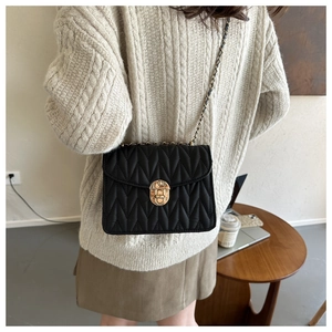 Schwarze Stepptasche mit goldener Kette am Model in gemütlicher Innenraum-Umgebung
