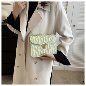 Detailaufnahme minzgrüne Stepptasche mit goldener Kette auf weißem Trenchcoat