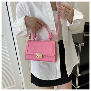 Detailed view of pink croc-embossed crossbody bag worn by a model in a modern office