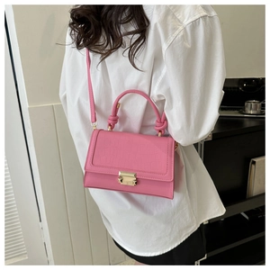 Detailed shot of pink faux leather bag with crocodile texture and knot handle on model