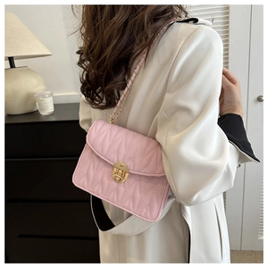Rosafarbene Stepptasche mit goldener Kette an Model im weißen Mantel getragen