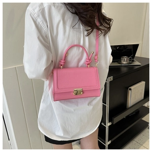 Detail view of pink crocodile pattern crossbody bag with knot handle and gold metal lock