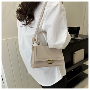 Detail of beige crossbody bag with croc-embossed texture and golden metal clasp