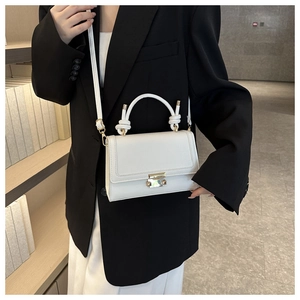 Detail of white crocodile texture crossbody bag with gold lock and knot handle on model