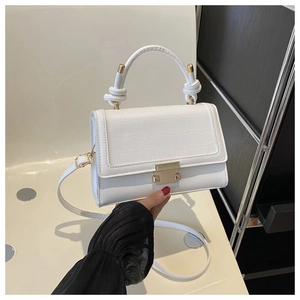 Detail showing white croc-effect embossed flap and golden metal clasp on stylish handbag