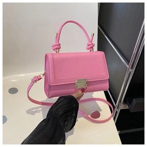 Close-up of pink crossbody bag with crocodile pattern texture and gold metal buckle