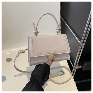 Detail of cream leather bag with faux crocodile flap and gold metal twist lock closure