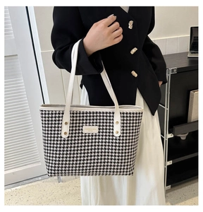 Detailed close-up of houndstooth tote bag with beige leather handles and gold studs