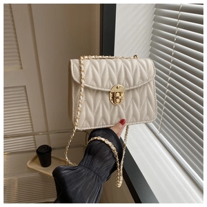 Detailansicht der beigen Stepptasche mit goldener Kette und V-förmigem Steppmuster-Design