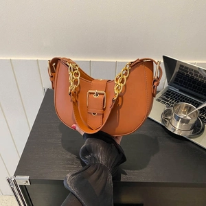 Vintage caramel brown hobo bag with gold chain strap on office desk setting