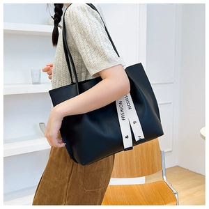 Side view of large black leather tote bag with white crossbody straps on model