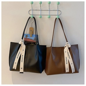 Detail view of large soft faux leather tote bags in black and brown with fashion straps