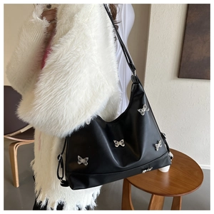 Détail du sac bandoulière en cuir souple avec breloques papillon et sangle réglable