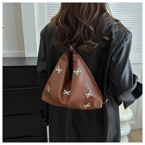 Gros plan détaillé du sac hobo en cuir marron avec ornements de papillons en métal argenté