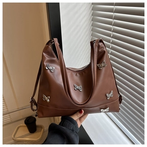 Détail d'un sac cabas marron souple avec papillons métalliques et aspect brillant