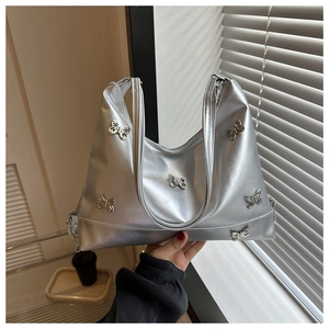 Détail du sac cabas argenté avec ornements de papillons en métal et fermeture éclair
