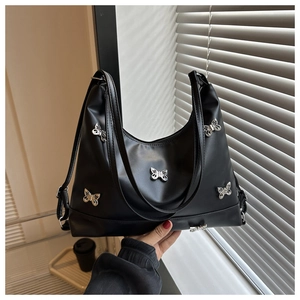 Gros plan d'un sac cabas en cuir noir avec clous papillon argentés et bandoulière