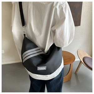 Rear view of model wearing black nylon crescent bag with fashion label and striped detail