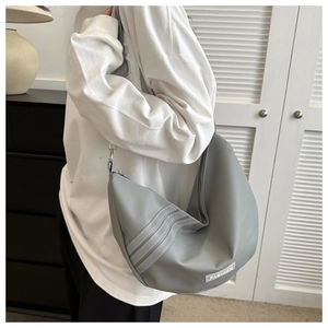 Detail of grey nylon crescent shoulder bag featuring three white stripes and fashion tag
