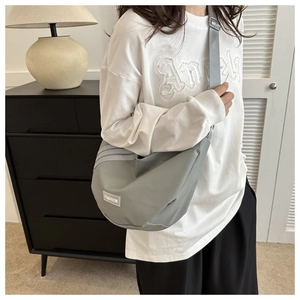 Detail of grey nylon crescent shoulder bag with adjustable strap and fashion label