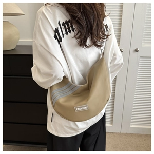 Detail view of khaki crescent shoulder bag with parallel gray stripes and fashion patch