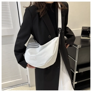 Detail of white nylon crescent bag with gray stripes and wide woven shoulder strap on model