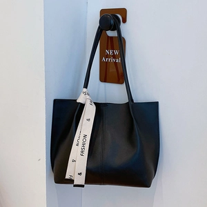 Large black matte leather tote bag with white fashion ribbon on a wall hanger