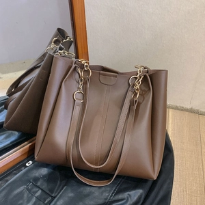 Retro dark brown matte leather tote bag with gold ring hardware on a wood floor
